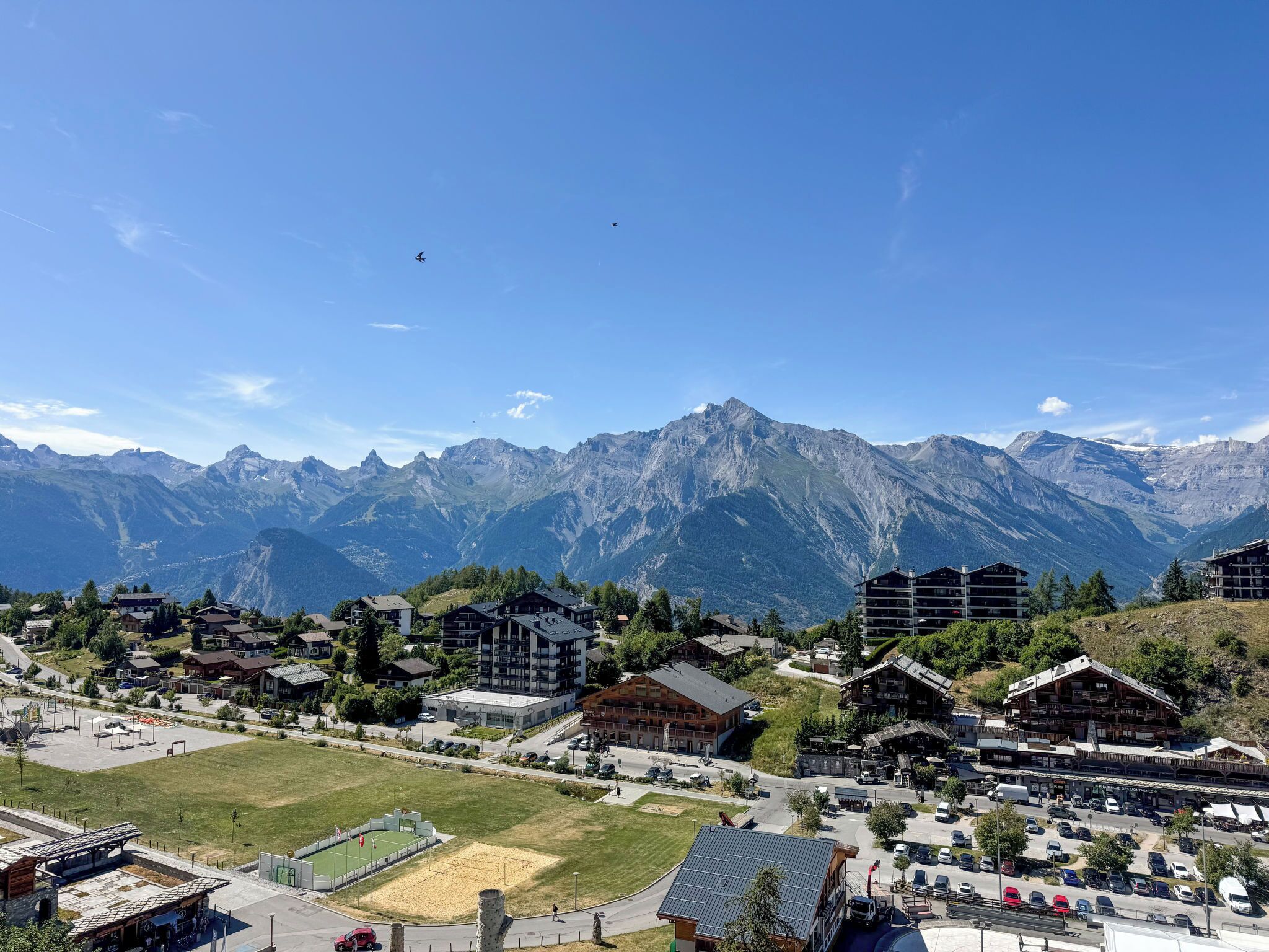 A mountainous town with traditional wooden buildings, a central open space, and a view of the mountains.