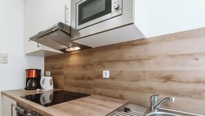 Uma cozinha moderna com uma pia de aço inoxidável, um micro-ondas e uma cafeteira sobre o balcão.