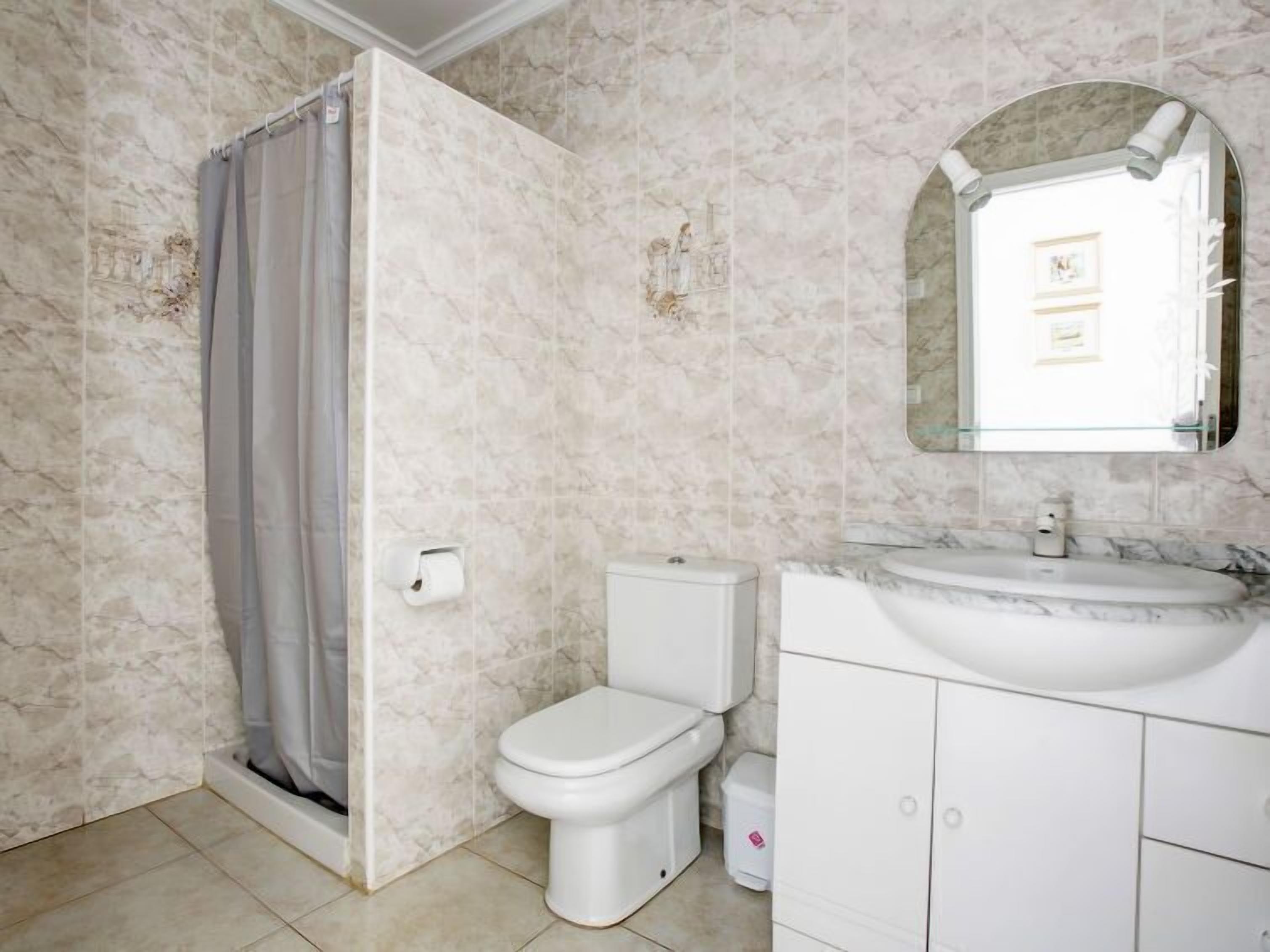 A bathroom with a toilet, sink, and shower curtain.
