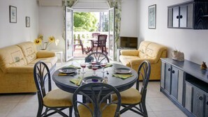 A dining area with a round table, chairs, and a sofa. There is a TV on a stand and a cabinet with drawers. - La Giralda by Interhome (Dénia)