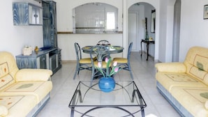 A spacious living room with a glass coffee table, yellow sofas, and a dining area with a round table and chairs. - La Giralda by Interhome (Dénia)