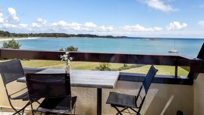 Un balcon avec une table et des chaises donnant sur une plage et l’océan.