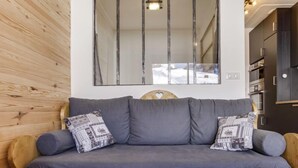 Ein Holzsofa mit grauen Kissen und gemusterten Zierkissen, ein Holz-Kopfteil und eine eingebaute Sitzbank.
