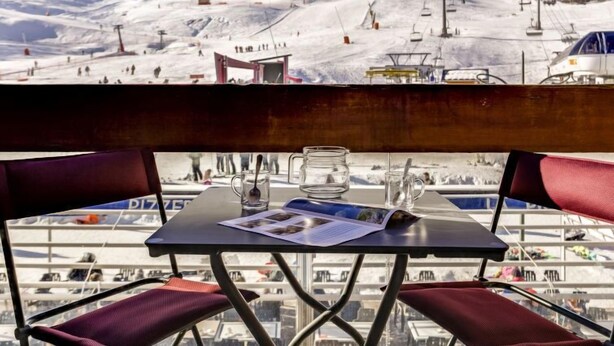 Ein Tisch mit Blick auf eine verschneite Berglandschaft, inklusive Skilifte und Sessellift.