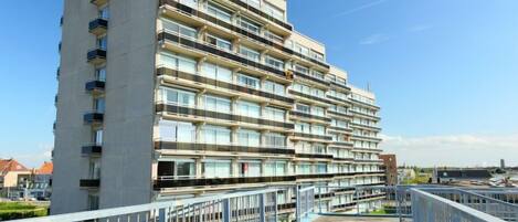 A multi-story hotel with balconies, a flat roof, and a clear sky.