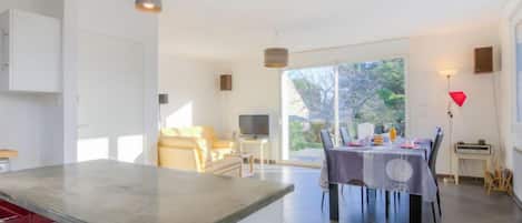 A modern kitchen with a dining area, large windows, and a view of the outdoors.