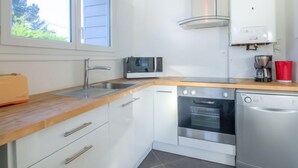 Una cocina moderna con armarios blancos, lavavajillas de acero inoxidable, horno, microondas y cafetera.