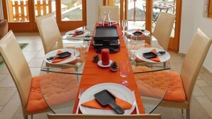 A dining area with a table set for four, equipped with a grill, wine glasses, and a red candle centerpiece. - Domaine des Reines B4 by Interhome (Nendaz)