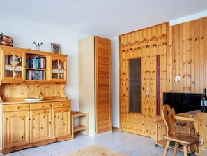 Um quarto de madeira com um armário, uma porta, uma televisão e uma cadeira.