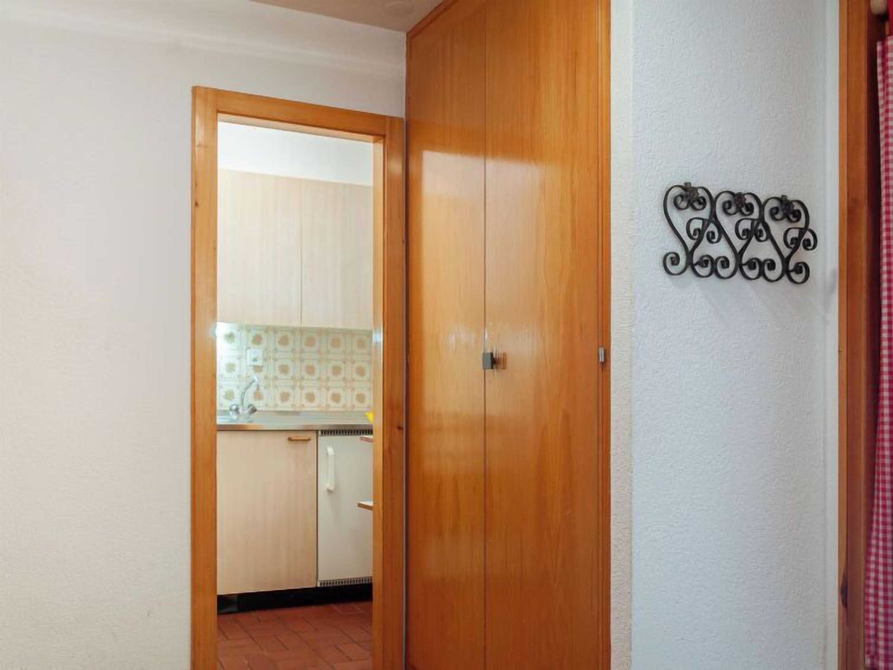 Ein Zimmer mit einem Holzschrank, einer Küchenzeile mit gemusterten Fliesen und einem dekorativen Metallkunstwerk an der Wand.