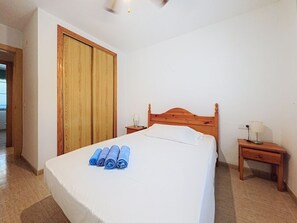 A bedroom with a wooden bed, a nightstand with a lamp, and a wooden wardrobe. - Residencial Daly by Interhome (Dénia)