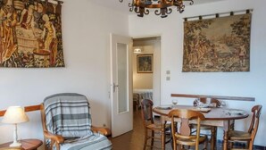 Un comedor con una mesa redonda de madera, seis sillas y un sillón a rayas. Un candelabro cuelga sobre la mesa.
