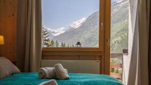 Una camera da letto con un letto, due asciugamani e una finestra vista montagne.