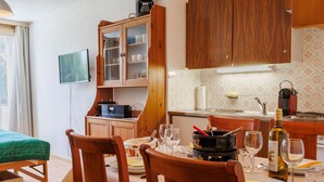 Un'accogliente zona pranzo con arredi in legno, un tavolo apparecchiato per due e un angolo cottura con pensili in legno e schienale piastrellato.