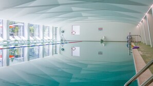 Una piscina interna con acqua cristallina, un trampolino e una postazione per il bagnino.