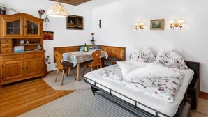 A bedroom with a bed, wooden furniture, a dining table, and a ceiling with a light fixture. - Dachstein Top 27 by Interhome (Flachau)