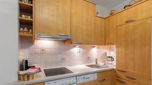 A kitchen with wooden cabinets, a built-in oven, a sink, and a coffee maker. - Dachstein Top 27 by Interhome (Flachau)
