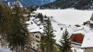 A snow-covered village with buildings, a frozen lake, and mountains in the background. - Parc C013 by Interhome (Champex)