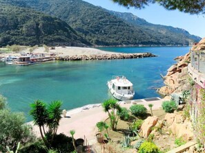 Un bateau était amarré dans une marina, le long d’une côte rocheuse, avec une chaîne de montagnes en arrière-plan.