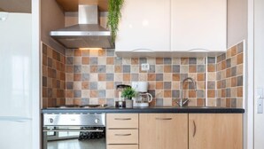 A modern kitchen with a stainless steel stove, wooden cabinets, and a tiled backsplash. - Apartment Casino by Interhome (Canet-Plage)