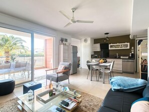 A modern apartment with a dining area, kitchen, and a balcony with a palm tree.