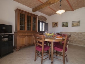 Un coin repas avec une table et des chaises en bois, un téléviseur et un meuble.
