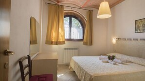 Une chambre à coucher comprenant un lit, une chaise, une fenêtre avec des rideaux, un radiateur et une lampe suspendue.