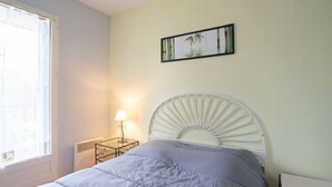 Una camera da letto con un letto, un comodino con una lampada, un quadro appeso al muro e una finestra.