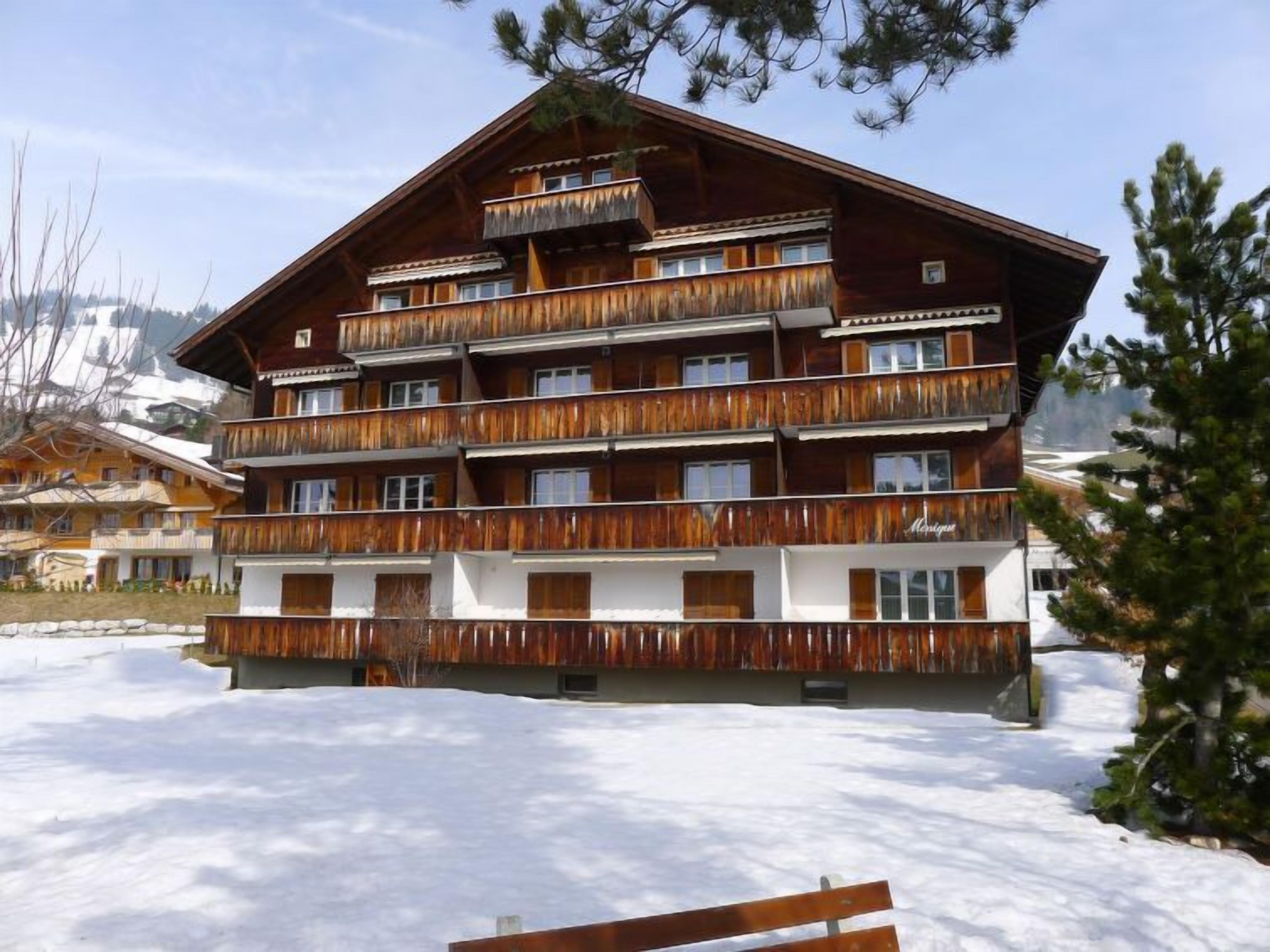 Un edificio de madera de varios pisos con balcones, rodeado de nieve.