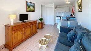 Un salon comprenant un canapé, un téléviseur, un meuble en bois et une petite table sur laquelle est posée une plante.