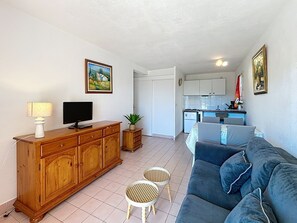 A living room with a sofa, a TV, a wooden cabinet, and a small table with a plant.