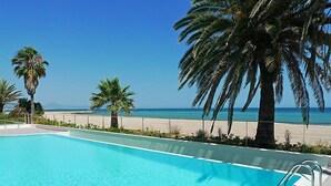 En klarblå pool med utsikt över stranden och palmerna.
