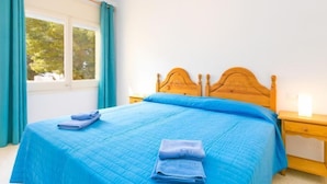 Un dormitorio con cama de madera, una mesita de noche y una ventana con cortinas.