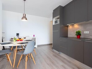 A modern kitchen with grey cabinets, a microwave, and a potted plant.