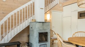 Un intérieur en bois avec une cheminée en pierre, des meubles en osier et un escalier blanc.