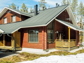 A cabin with a sloped roof, large windows, and a wooden deck.