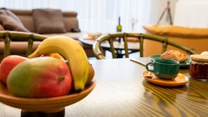 A dining table with a bowl of fruit, a green mug, and a jar of jam. - Vacation home Butzel by Interhome (Norddeich)