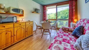 A cozy room with a wooden cabinet, a microwave, a television, and a bed with a quilt.