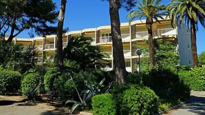 Un hôtel à plusieurs étages doté de balcons, entouré d’une végétation luxuriante et de palmiers.