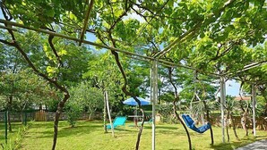 Un giardino con un'amaca, un'altalena e un ombrellone blu.