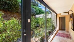 Um corredor com grandes portas de vidro que dão para uma área de jardim.