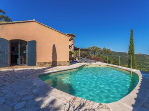 A swimming pool with clear water, a stone pathway, and a building with a door and windows.
