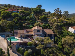 Une villa de style méditerranéen dotée d’une piscine, d’un toit recouvert de tuiles en terre cuite et d’une végétation luxuriante.