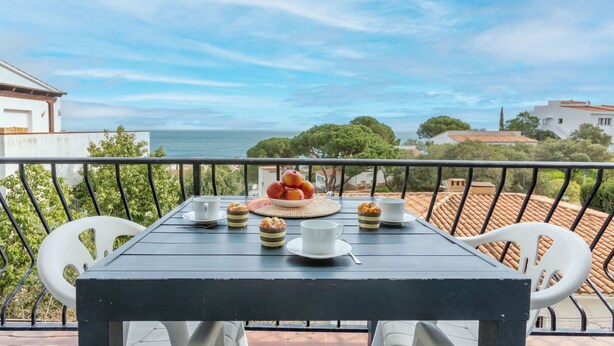 Un balcon avec une table préparée pour le thé, offrant une vue sur la côte.