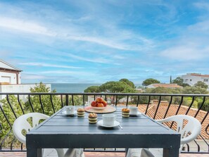 Ein Balkon mit einem nach Kaffee und Kuchen gedecktem Tisch, mit Blick auf die Küste.