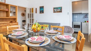 Un coin repas avec une table en verre, dressée pour six personnes, entourée de chaises en bois.