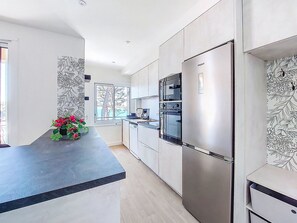 Uma cozinha moderna com eletrodomésticos de aço inoxidável, bancada preta e janela com vista.