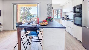 Une cuisine moderne avec un coin repas, de grandes fenêtres et une vue sur l’extérieur.