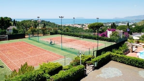 Een tennisbaan met vrij uitzicht op de zee en omliggend groen.