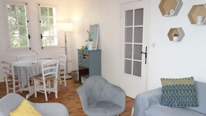 A living room with a grey sofa, a grey armchair, and a yellow pillow. There is a dining table with white chairs. - Hameau la Madrague by Interhome (Saint Cyr sur Mer La Madrague)